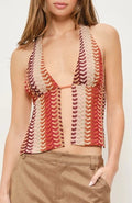Woman wearing a patterned top and beige shorts against a white background