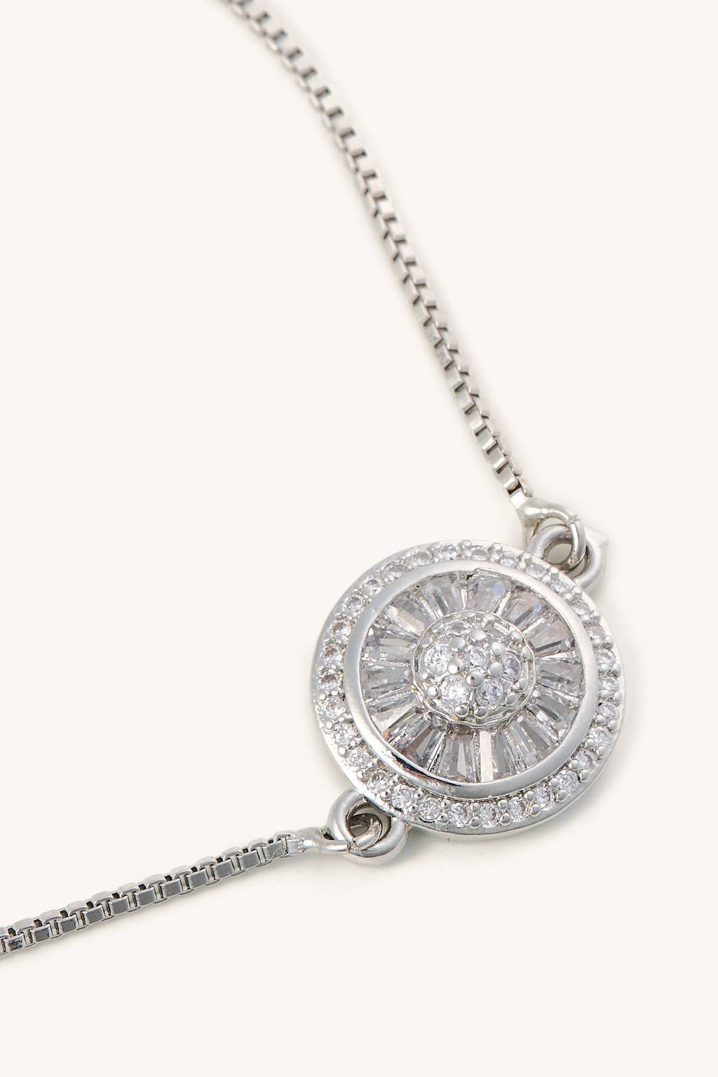 Silver necklace with a round pendant on a white background