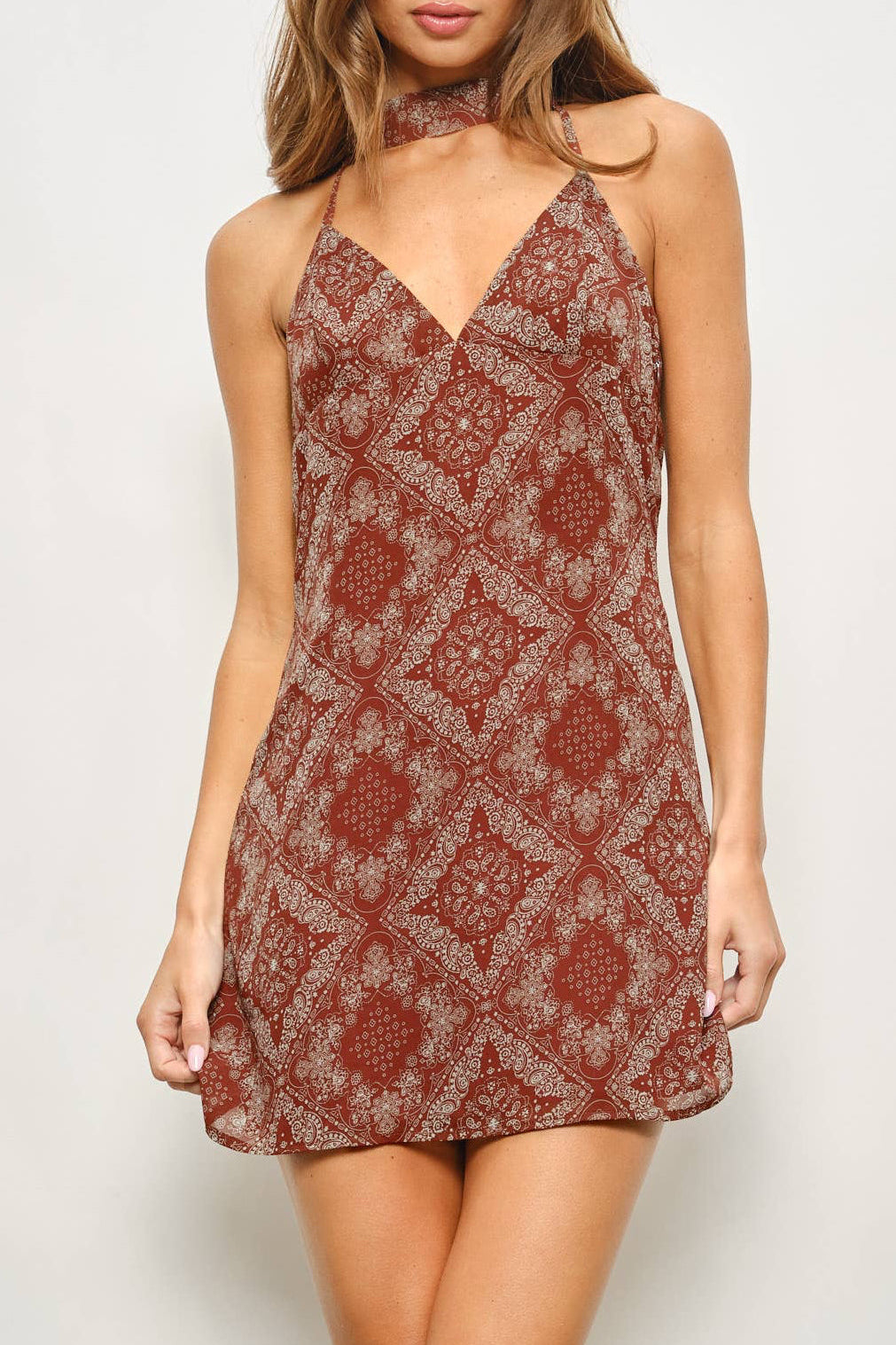 Woman wearing a patterned slip dress against a plain background
