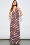 Woman wearing a brown dress with blue polka dots against a white background
