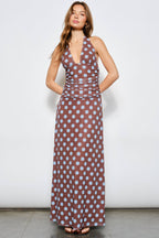 Woman wearing a brown dress with blue polka dots against a white background
