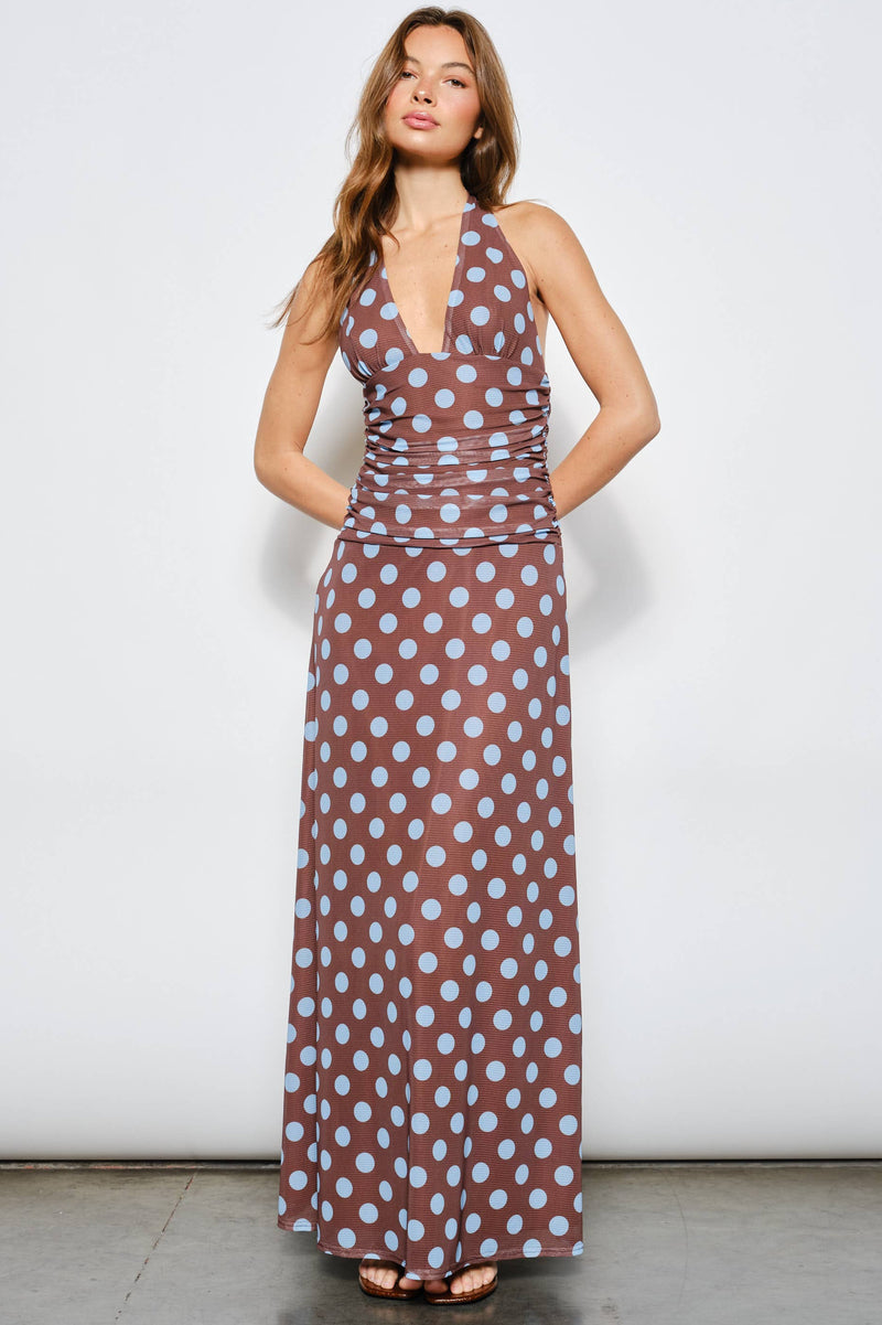 Woman wearing a brown dress with blue polka dots against a white background