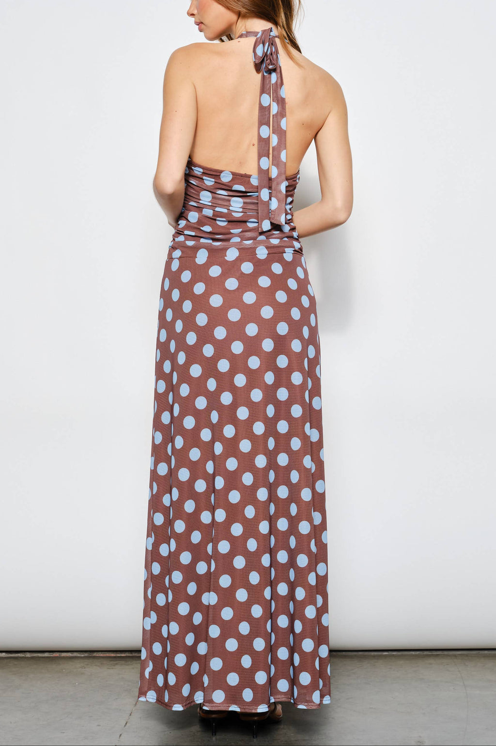 Woman wearing a long polka dot dress with a white background