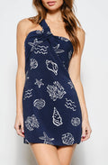 Woman wearing a navy blue dress with white patterns against a white background