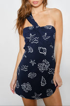 Woman wearing a navy blue dress with white patterns on a white background