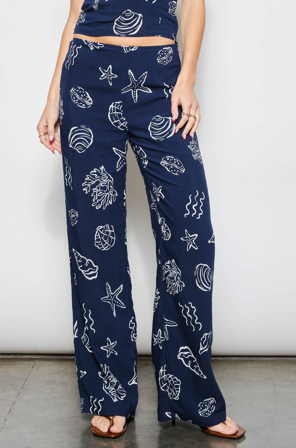Woman wearing a navy blue outfit with white patterns on a plain background