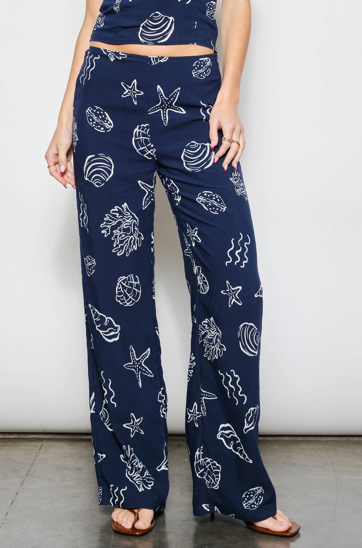 Woman wearing a navy blue outfit with white patterns on a plain background