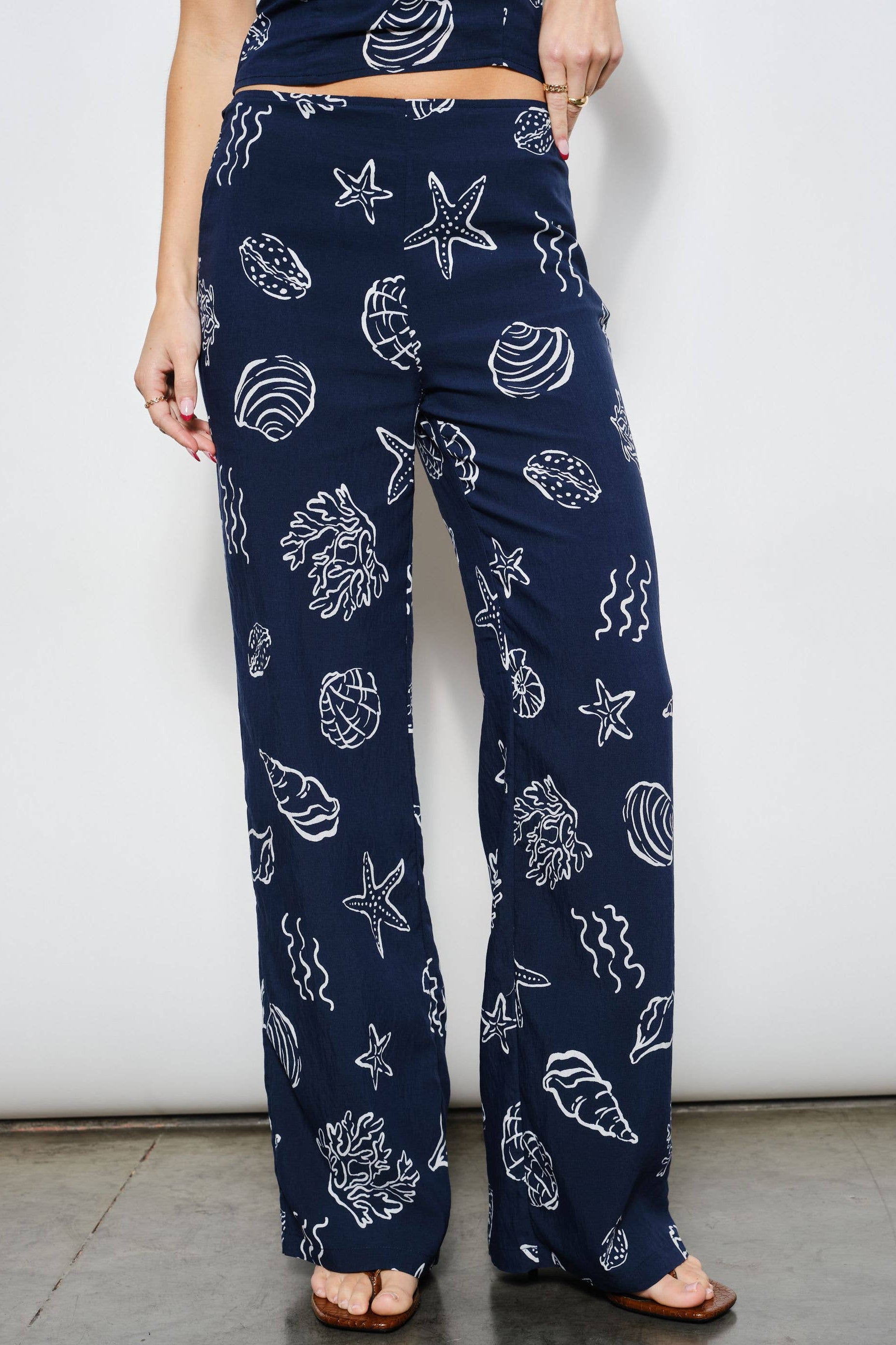 Navy blue pants with white shell pattern worn by a person against a white background