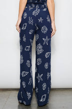 Woman wearing a navy blue jumpsuit with white patterns on a white background