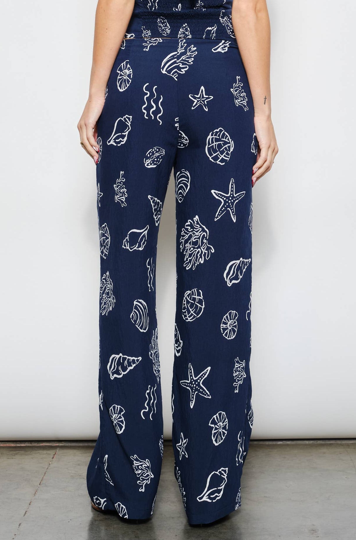 Woman wearing a navy blue jumpsuit with white patterns on a white background