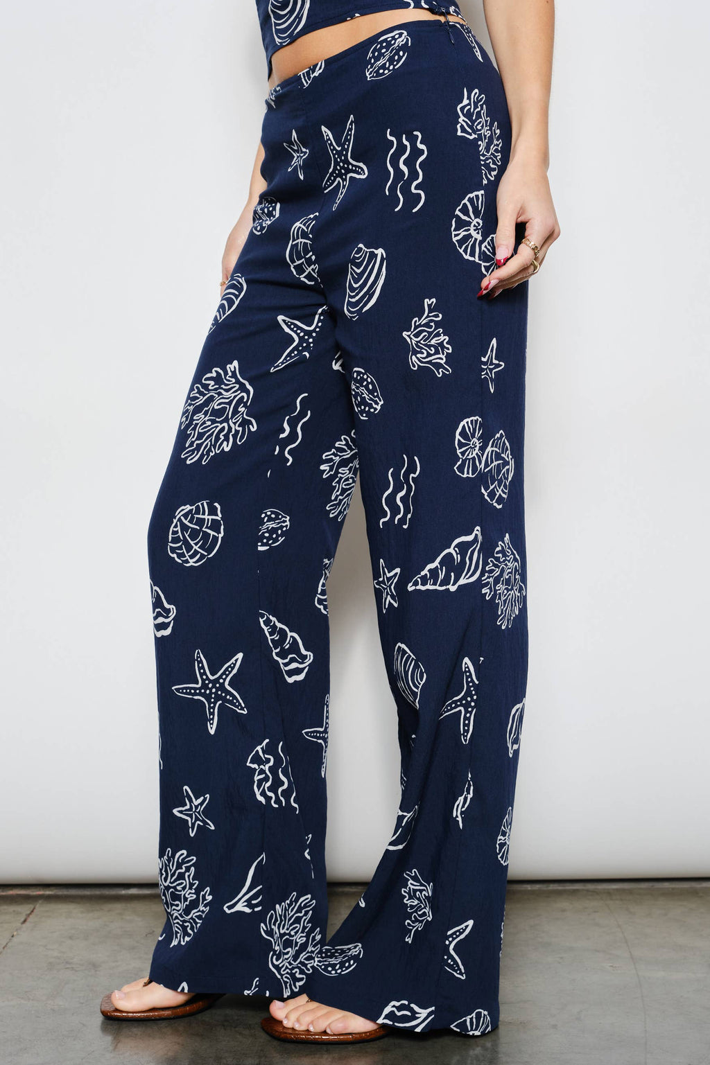 Navy blue pants with white sea creature pattern worn by a person against a plain background
