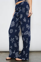 Navy blue pants with white sea creature pattern worn by a person against a plain background