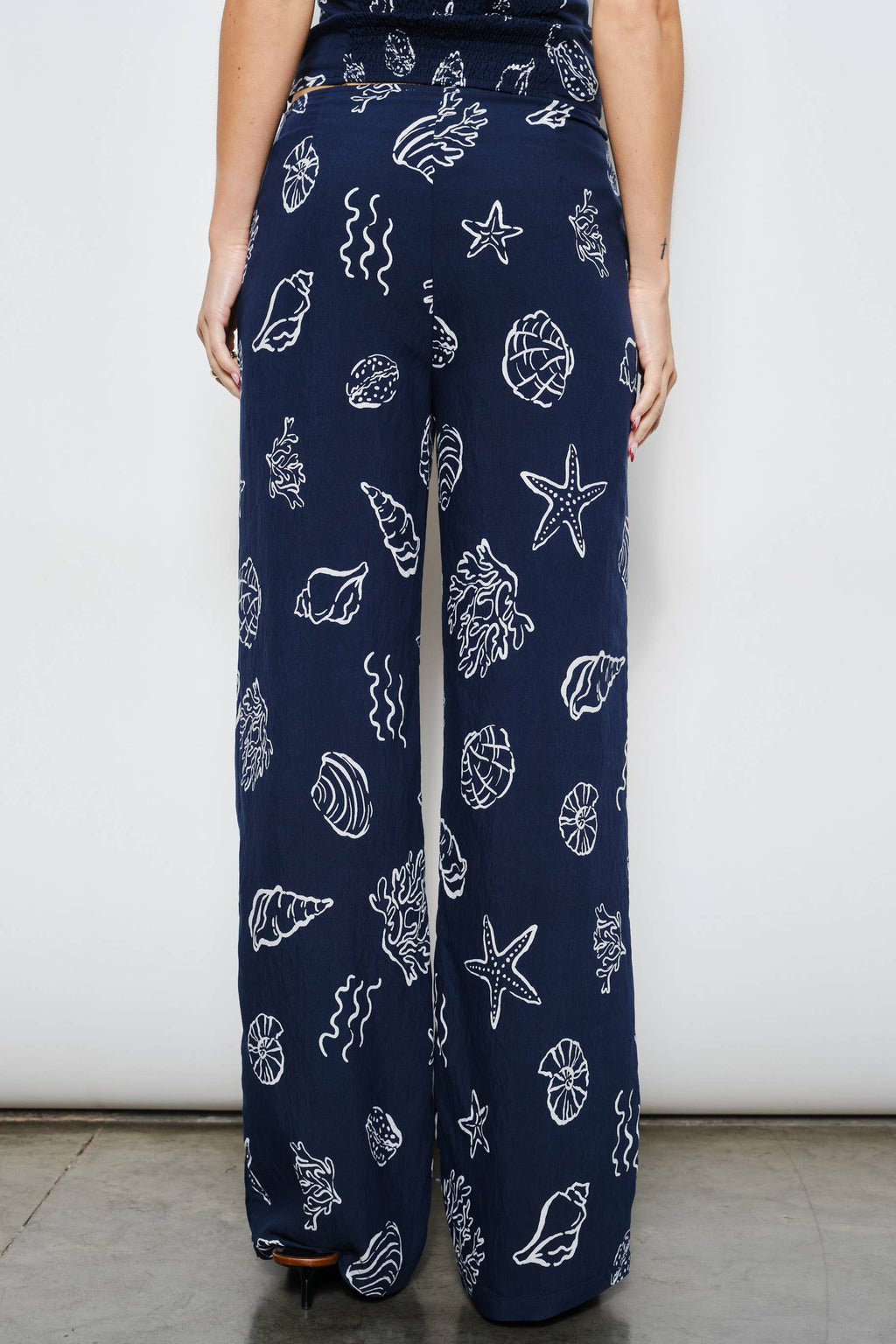 Navy blue pants with white sea-themed pattern worn by a person against a plain background