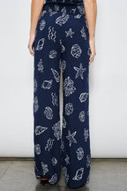 Navy blue pants with white sea-themed pattern worn by a person against a plain background