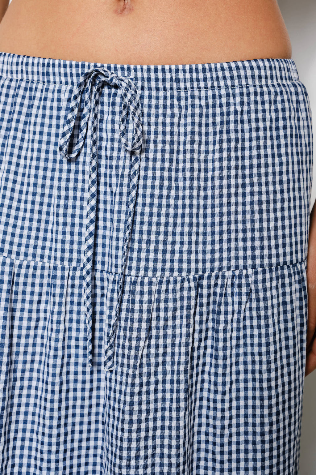 Close-up of blue and white checkered pants with a drawstring waistband.