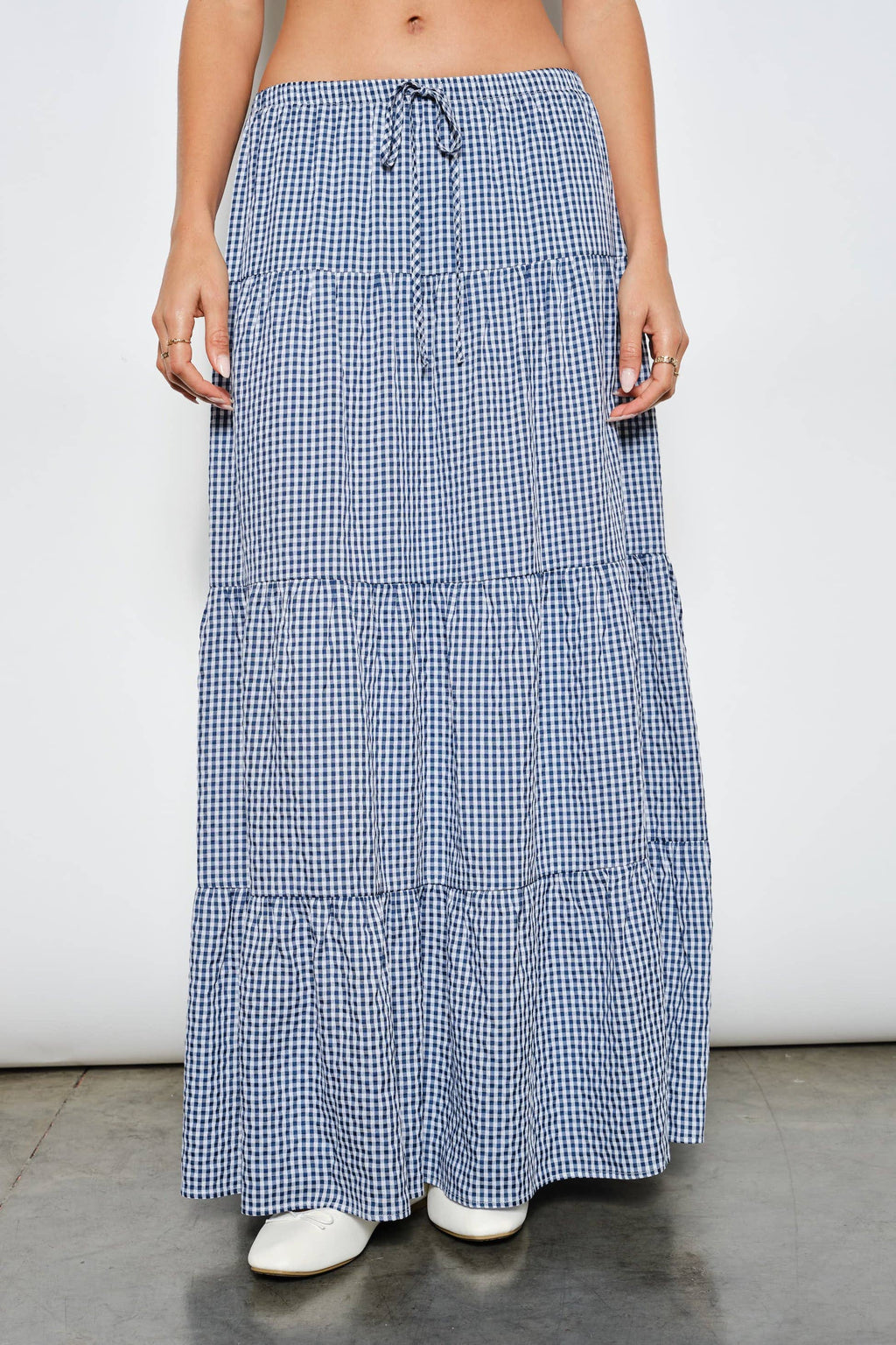Person wearing a blue and white checkered skirt on a plain background