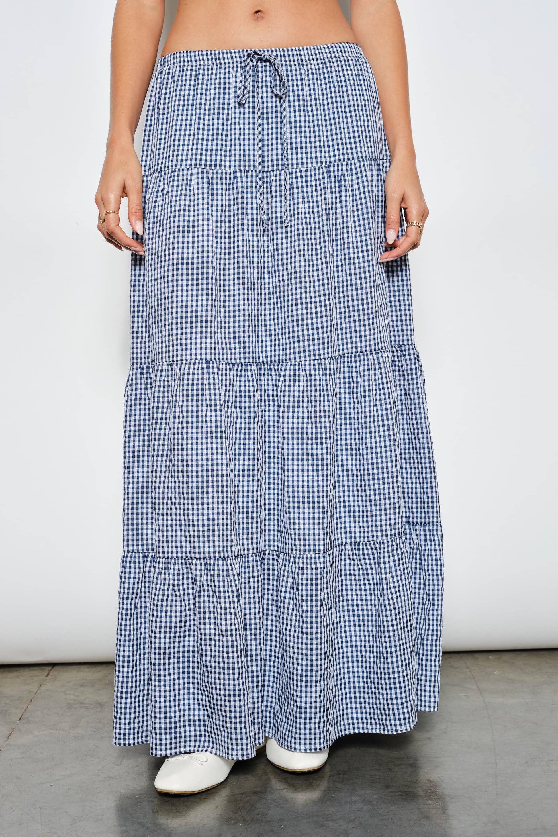 Person wearing a blue and white checkered skirt on a plain background