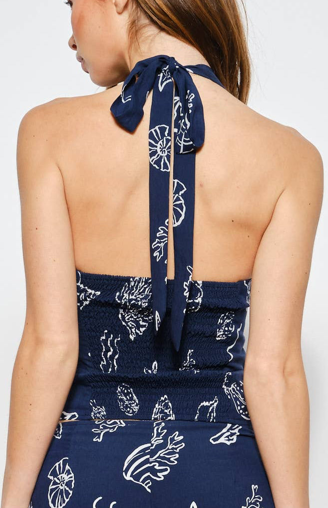 Woman wearing a navy blue halter with white patterns on a white background