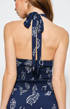 Woman wearing a navy blue halter with white patterns on a white background