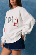 Woman wearing a white sweatshirt with graphic designs against a blue background