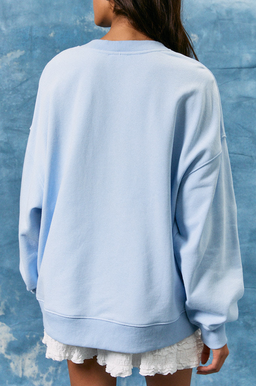 Person wearing a light blue sweatshirt against a textured blue background