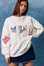 Woman wearing a white sweatshirt with graphic designs on a blue background