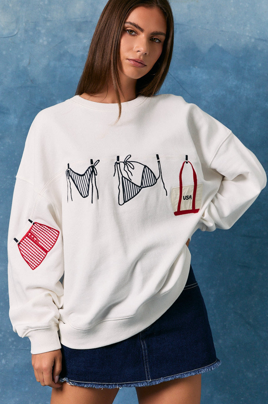 Woman wearing a white sweatshirt with graphic designs on a blue background