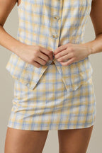 Woman wearing a yellow and blue checkered skirt against a beige background