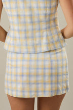 Woman wearing a yellow and blue plaid skirt against a beige background