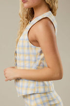 Person wearing a yellow and blue plaid vest on a neutral background