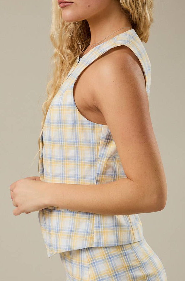 Person wearing a yellow and blue plaid vest on a neutral background