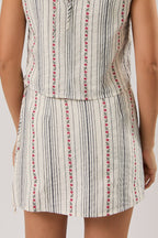Woman wearing a sleeveless skort with a striped pattern on a plain background