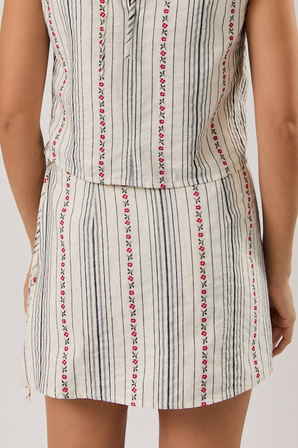 Woman wearing a sleeveless skort with a striped pattern on a plain background