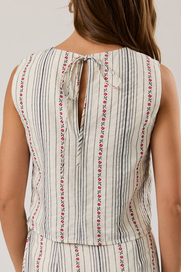 Woman wearing a sleeveless top with a striped pattern on a plain background