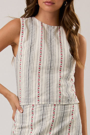 Woman wearing a sleeveless plaid top with black boots on a plain background