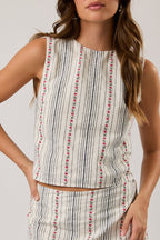 Woman wearing a sleeveless striped top on a plain background