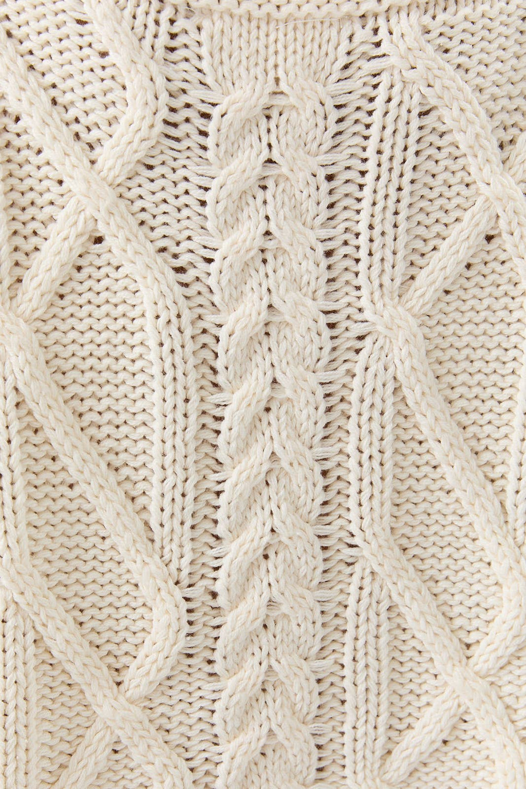 Close-up of a beige knitted fabric with a cable pattern