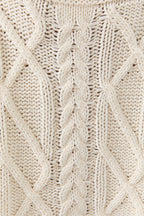 Close-up of a beige knitted fabric with a cable pattern