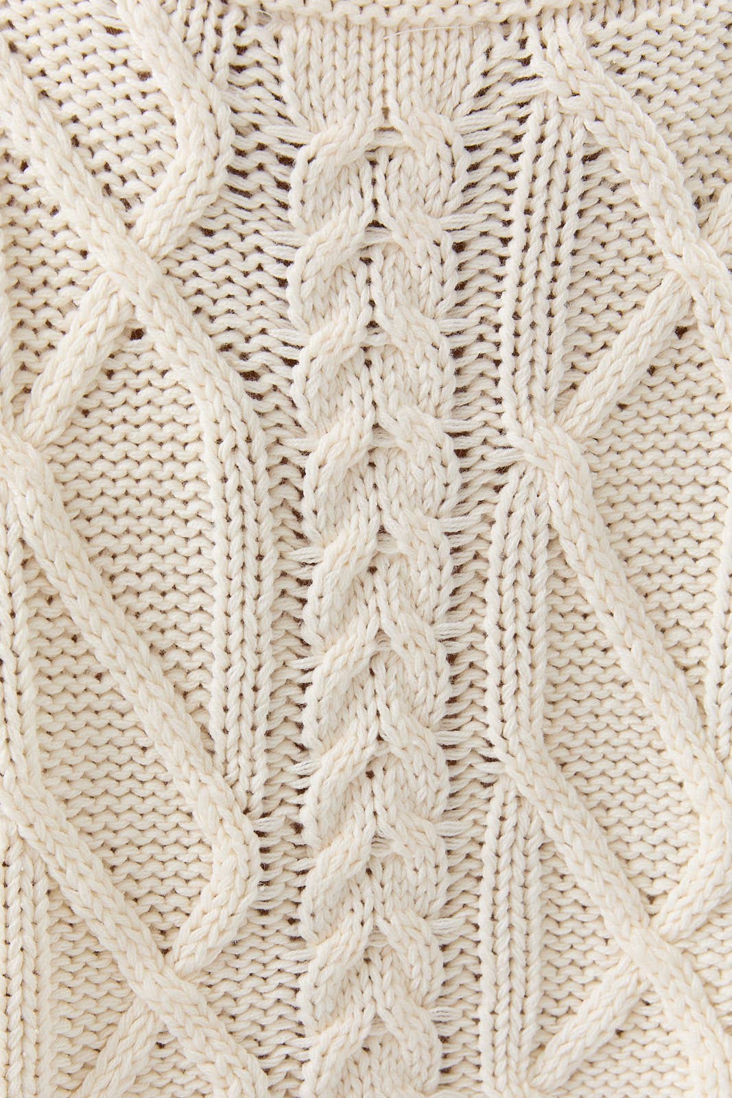 Close-up of a beige knitted fabric with a cable pattern