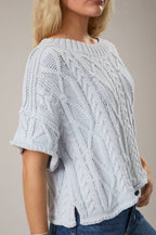 Woman wearing a light blue knitted sweater and jeans on a beige background