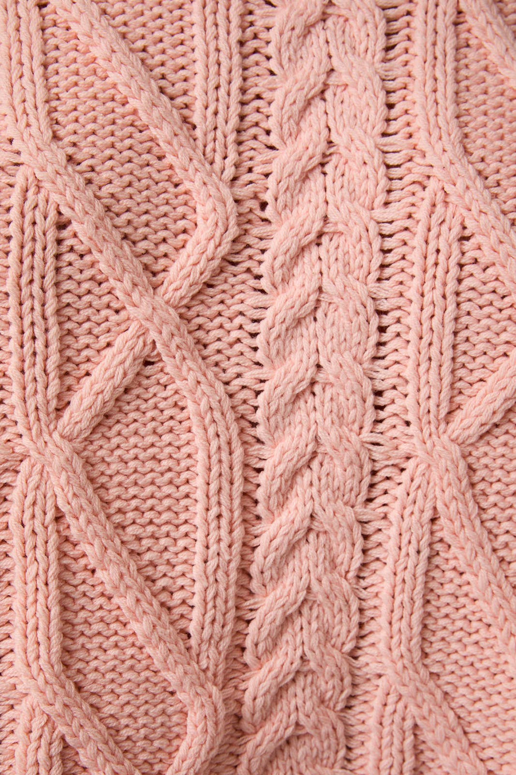 Close-up of pink knitted fabric with cable pattern