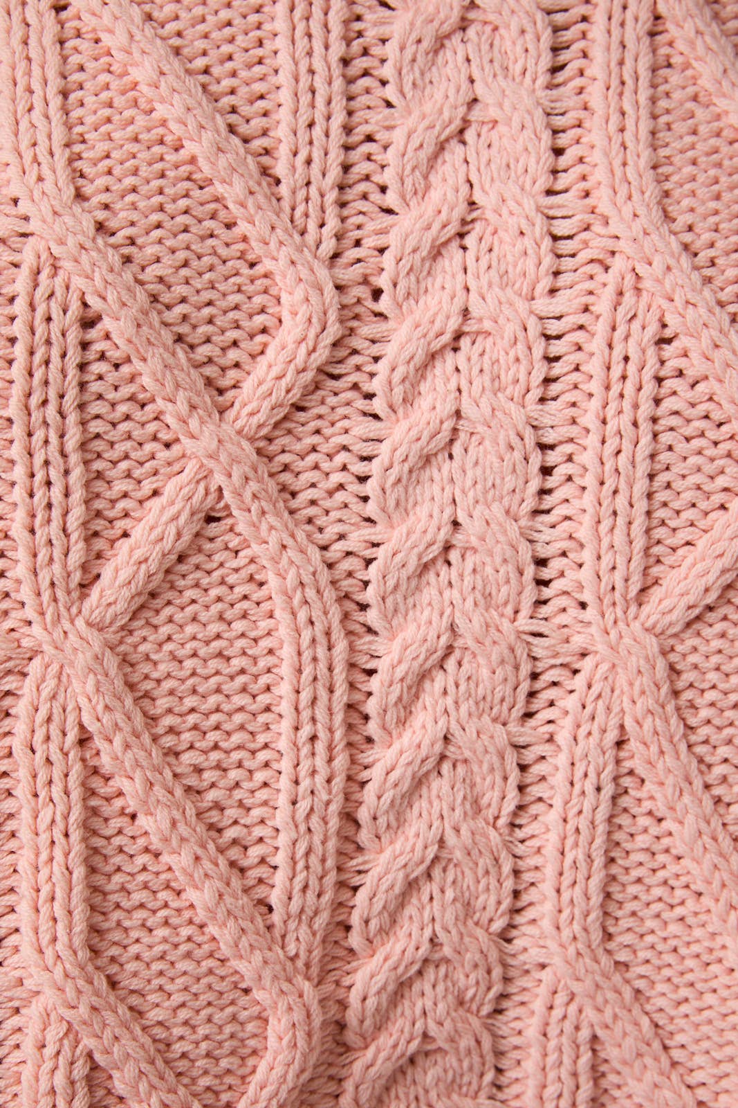 Close-up of pink knitted fabric with cable pattern