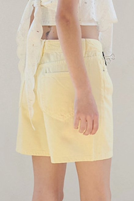Woman in a white top and yellow skirt standing in a room with a neutral color scheme.