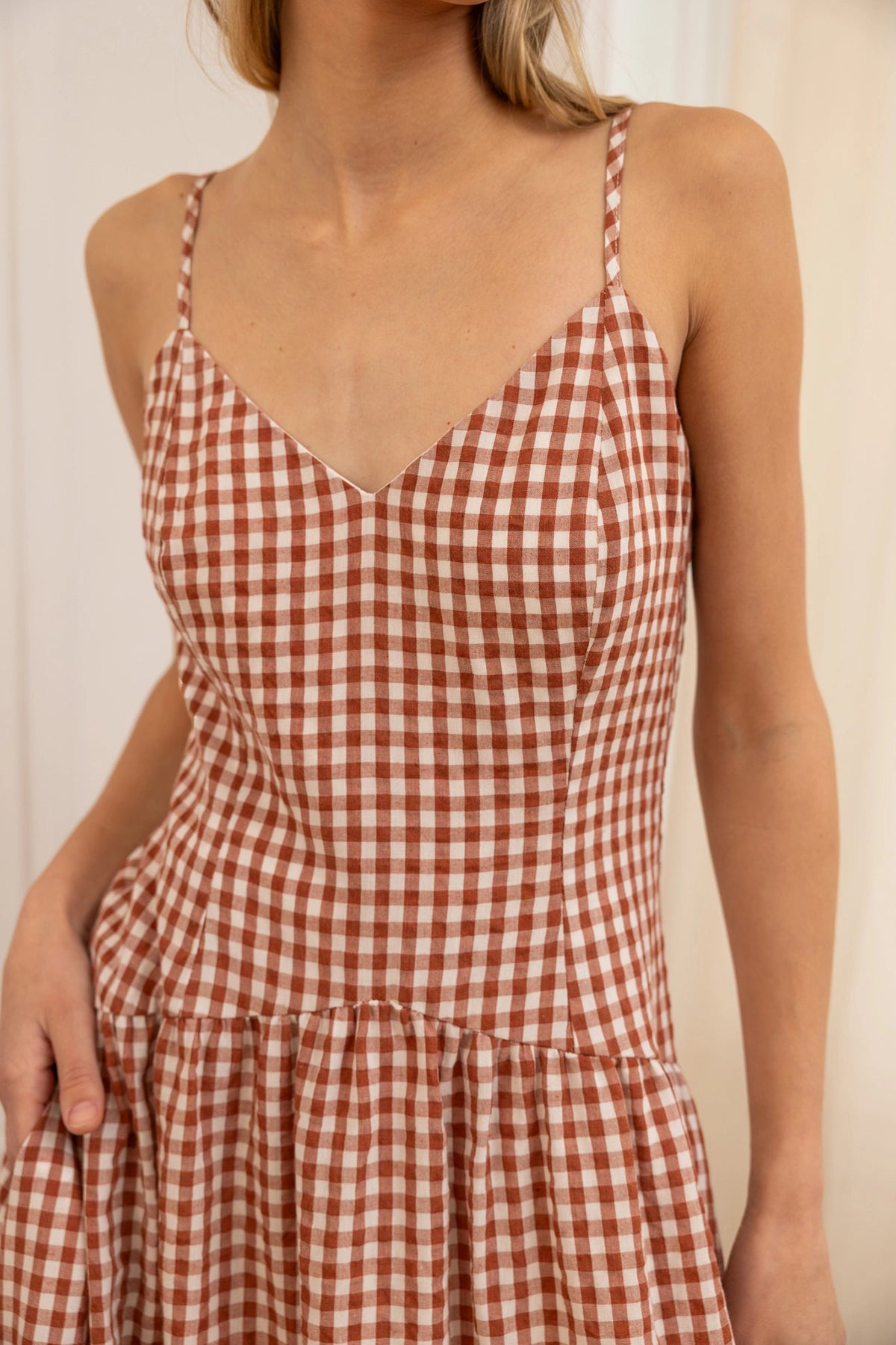 rust and white checkered dress worn by a person against a neutral background