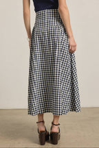 Person wearing a navy and white checkered skirt with a plain background