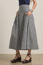 Woman wearing a navy top and navy and white checkered skirt on a plain background