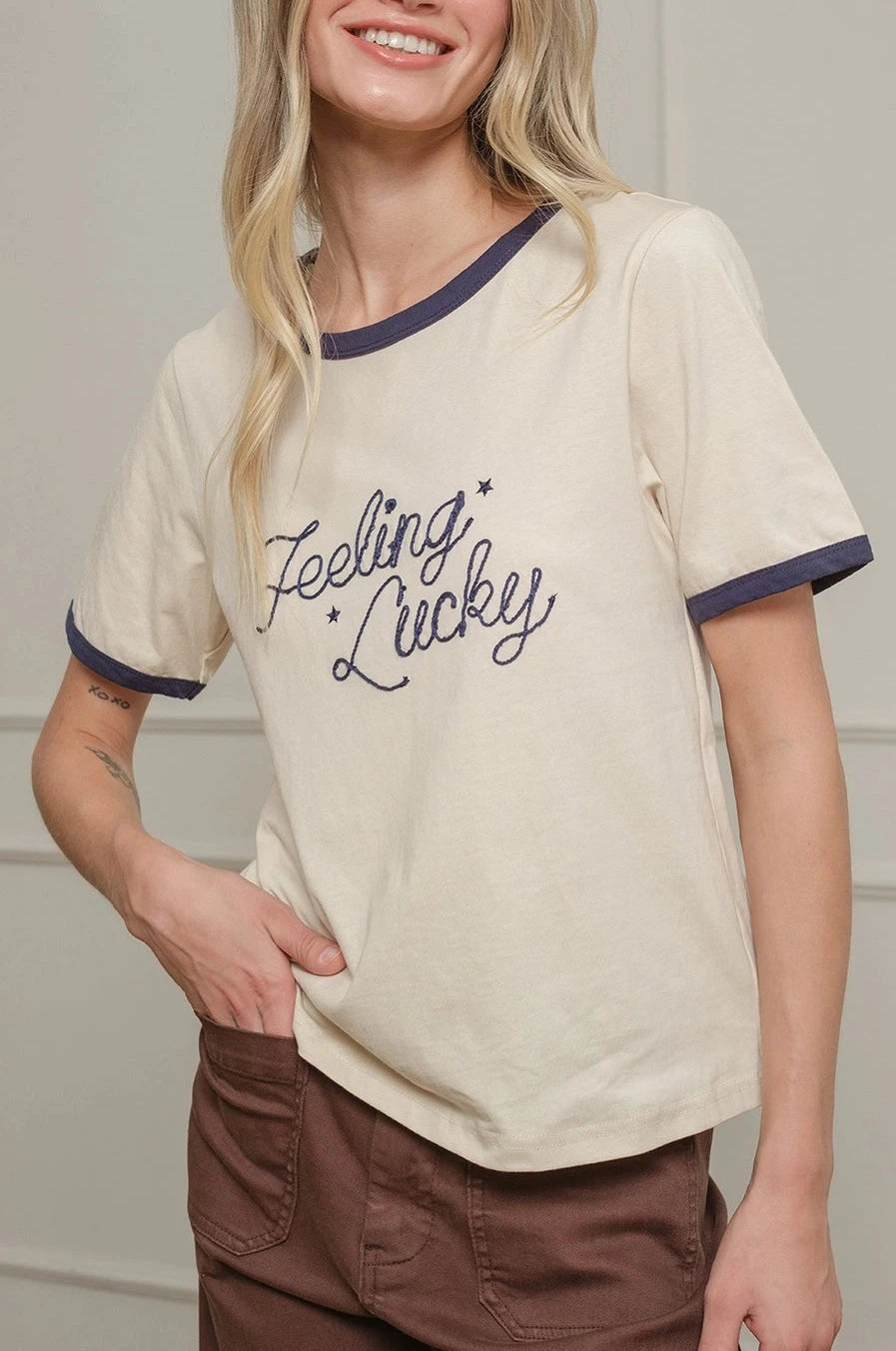 Woman wearing a 'Feeling Lucky' t-shirt against a plain background