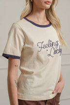 Woman wearing a cream t-shirt with 'Feeling Lucky' text against a plain background