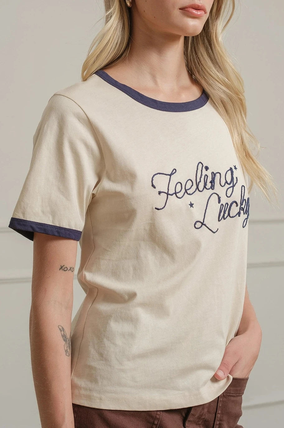 Woman wearing a cream t-shirt with 'Feeling Lucky' text against a plain background