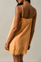 Woman wearing a mustard yellow slip dress against a neutral background